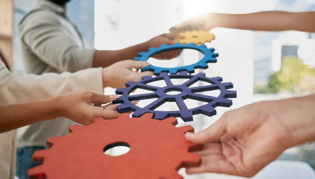 Business people, toys and gears at job for teamwork, sign or symbol with solution, trust and solida.